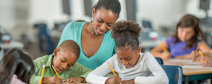 Teacher helping two young children with school work
