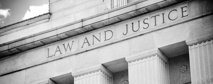 Front of courthouse with classical columns and text that reads law and justice