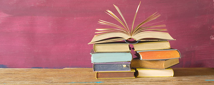 Stack of books on a table with the top book open