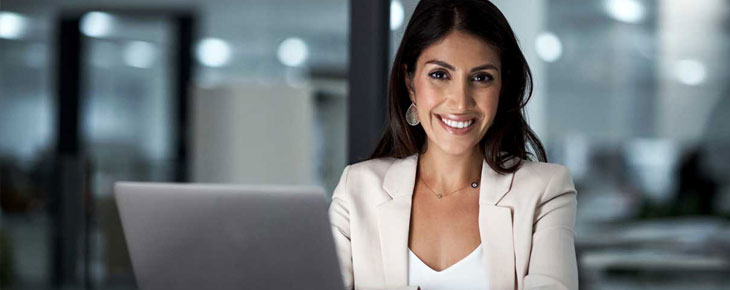 Professional woman sitting at a desk with her laptop.