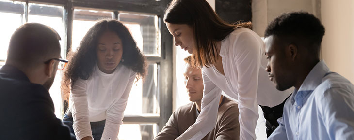 Focused diverse team discuss paperwork and share ideas